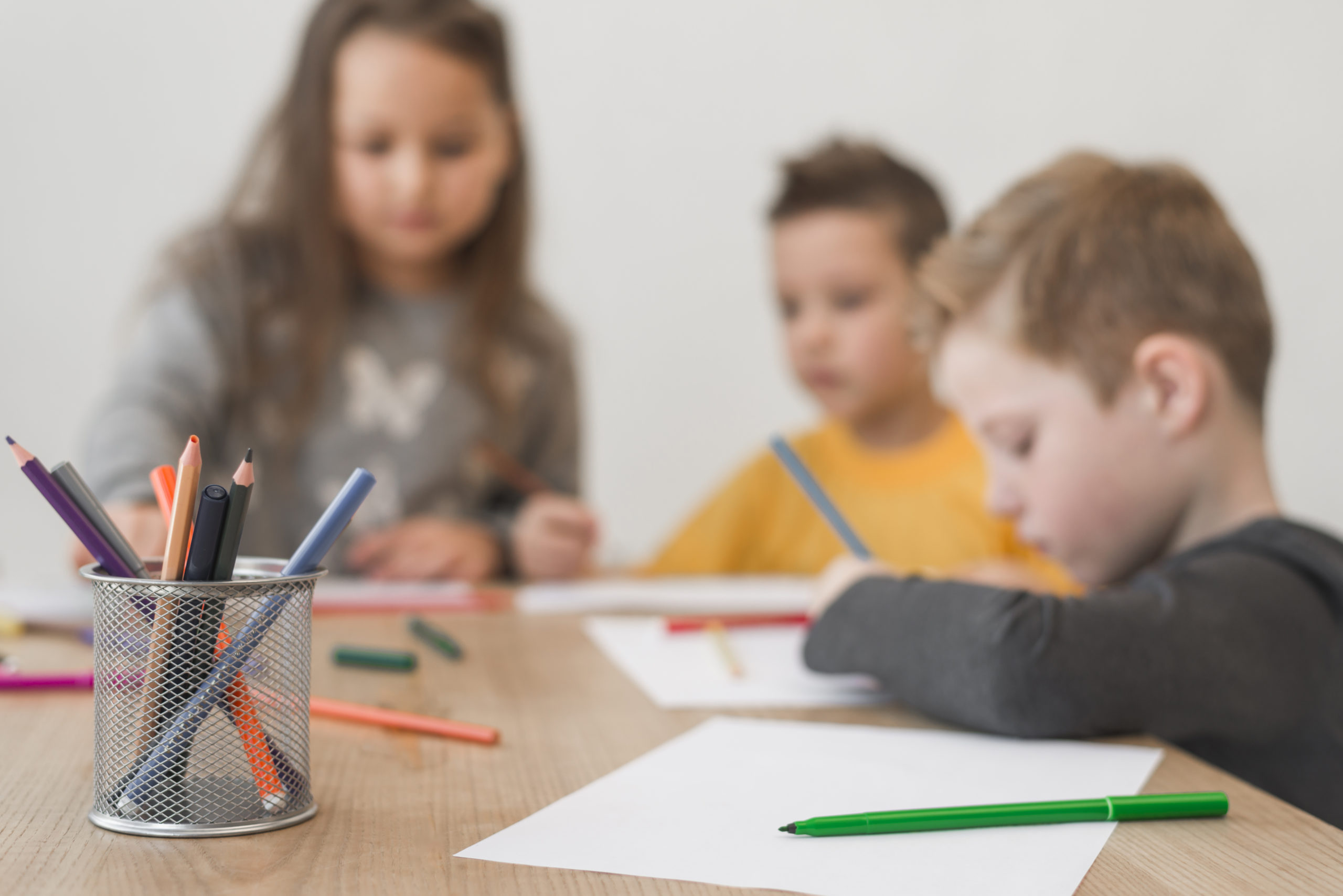 de sentants sont assis à table et dessinent avec des crayons de couleurs