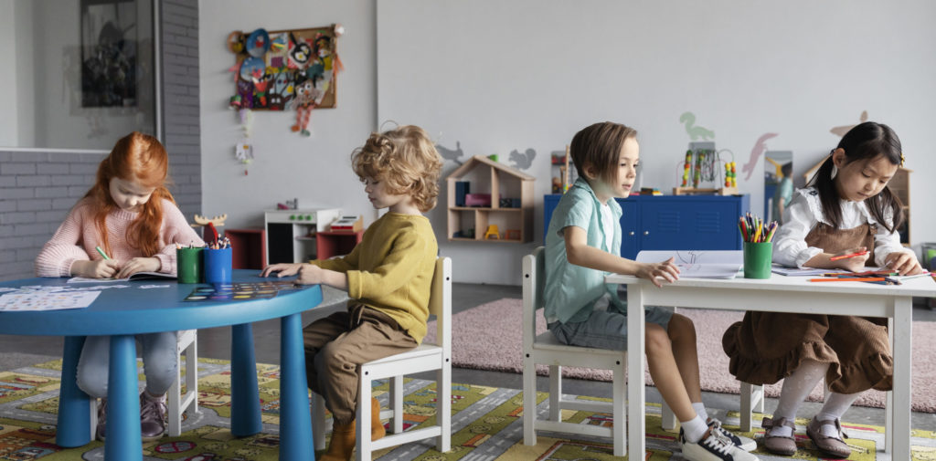 Des enfants sont assis à table, en train de colorier des dessins